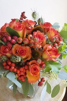 designed by Bella Fiori. fall centerpiece of confetti roses, rose hips, hypericum berries, mountain ash berries, coneflower, nigella pods, seeded eucalyptus